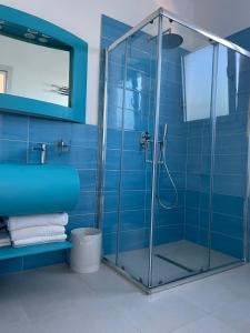 y baño con ducha de azulejos azules. en Seashell Guest House, en Torre Marino