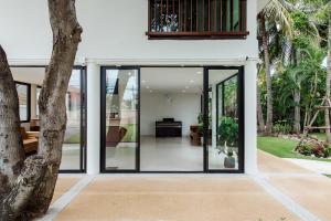 an open pivot door of a house with glass at Prinz Garden Villa in Hua Hin