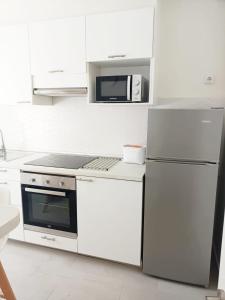 a white kitchen with a refrigerator and a microwave at AREAS NEGRAS- Apartamento centro de Cedeira. in Cedeira