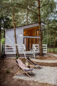 a couple of chairs sitting in front of a tiny house at Wiejskie Swawole-domki w lesie na wsi 