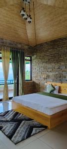 a bedroom with a large bed and a brick wall at Rudra Himalayan Retreat in Almora