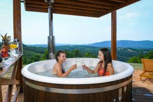 Vila Promaja في كلادوفو: كانتا جالستين في حوض استحمام ساخن مع كؤوس من النبيذ