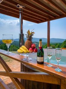 Vila Promaja في كلادوفو: طاولة مع كؤوس وزجاجة من النبيذ والفاكهة