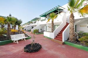 a row of houses with palm trees and a bench at Los Pocillos in Los Pocillos