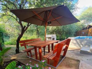 uma mesa de piquenique com um guarda-sol ao lado de uma piscina em Kanimambo Chalet em Marloth Park