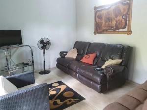 uma sala de estar com um sofá de couro preto e um tapete em Kanimambo Chalet em Marloth Park