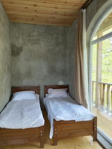 two twin beds in a room with a window at Lento Kaldani Guesthouse in Adishi