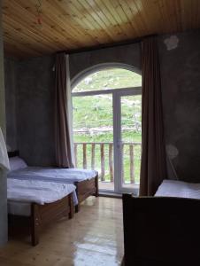 two beds in a room with a large window at Lento Kaldani Guesthouse in Adishi