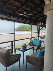a room with a table and chairs and a view of the ocean at Joets Guesthouse in Bogmalo