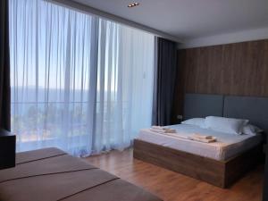 a bedroom with a bed and a large window at Le Rêve Boutique Hotel in Dhërmi