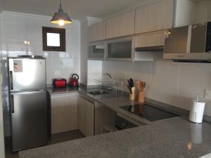 a kitchen with a stainless steel refrigerator and cabinets at Departamento Jardin del Mar La Serena in Coquimbo