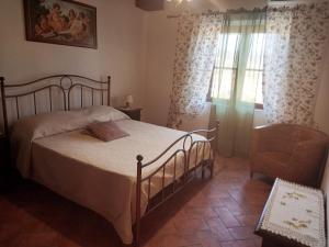 um quarto com uma cama, uma cadeira e uma janela em Agriturismo La Casina em Saturnia