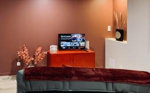 a living room with a television on a red cabinet at Gignac - Superbe cocon indépendant avec balnéo et jardin in Gignac