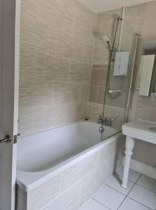 a white bathroom with a tub and a sink at Rainworth Lodge in Nottingham