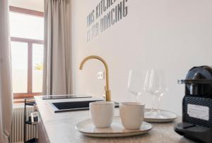 a kitchen counter with two cups and wine glasses at City Lounge Appartement am Hauptbahnhof in Sankt Pölten