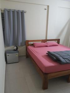 a bedroom with a bed with pink sheets and a window at Castle JP Deluxe in Bangalore