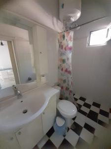 Baño blanco con aseo y lavamanos en Stafida Guesthouse - Myrtò, en Finikounta