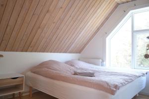 sypialnia z białym łóżkiem i drewnianym sufitem w obiekcie Noah's Ark w mieście Klitmøller
