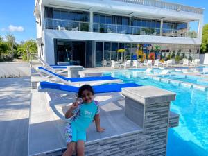 a little girl standing next to a swimming pool at Bingo House Watamu, A Modern 5-Bedroom Villa with Pool, A Kids Heaven in Watamu