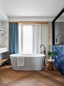 a bathroom with a large tub in front of a window at Kimpton Vividora Hotel by IHG in Barcelona
