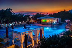 a view of a pool at sunset with a bar at Family Hotel La Luna - All inclusive in Lun