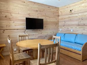 a dining room with a table and a blue couch at PLAGNE BELLECOTE - 5 Pers - Vue Pistes - Acces Piscine chauffee in Plagne Bellecote