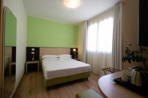 una camera con un letto bianco e una finestra di Hotel Ostuni a Rimini