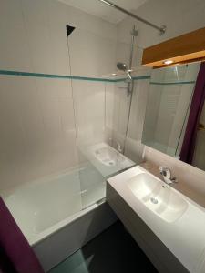 La salle de bains est pourvue d'un lavabo, d'une baignoire et d'un miroir. dans l'établissement PLAGNE BELLECOTE - 5 Pers - Vue Pistes - Acces Piscine chauffee, à Plagne Bellecôte
