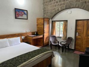 een slaapkamer met een bed en 2 stoelen en een raam bij The Green Gate Resort Mulshi in Pune