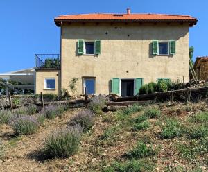 une maison sur une colline avec de la lavande devant elle dans l'établissement Agriturismo Cascina Cornelli, à Sassello