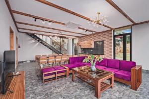 ein Wohnzimmer mit lila Sofas und einem Tisch in der Unterkunft Villa de Montana in Ba Vì