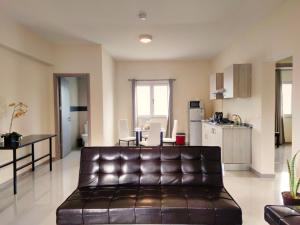 Praia Capital Residence Aparthotel في برايا: غرفة معيشة مع أريكة جلدية ومطبخ