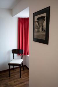 einen Stuhl in einem Zimmer mit einem roten Vorhang in der Unterkunft Gasthof Löwen Herznach in Herznach