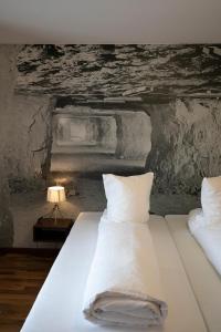 uma cama com lençóis brancos e almofadas num quarto em Gasthof Löwen Herznach em Herznach