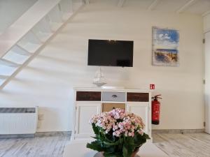 a living room with a tv and flowers on a table at Melroce Holiday Cottage 5503 in Bredene