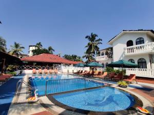a pool at a resort with chairs and umbrellas at Colonia Santa Maria in Baga