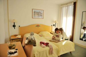 Village Vacances La Forêt des Tines في شامونيه مون بلان: بنتين جالسات على سرير في غرفة الفندق