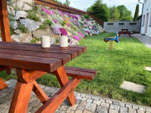 una mesa de picnic de madera en un jardín con flores en Rodinný penzion MARMAR en Staré Město
