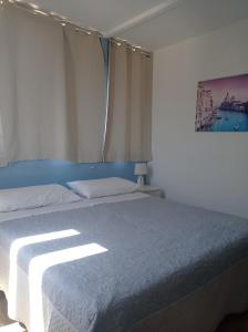 a bedroom with a bed with the sun shining on it at Casa Piano Ponente in Isola delle Femmine