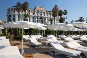 a bunch of white chairs and umbrellas in front of a building at Hotel Le Negresco in Nice