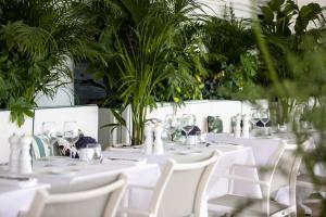 a table with white tables and chairs and plants at Hotel Le Negresco in Nice