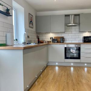 a kitchen with white cabinets and a wooden floor at Modern 2 Bed Apartment/Free Parking/Near City/Self-Check In in Handsworth