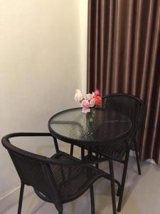 a glass table with two chairs and a vase with flowers at Life&Love Resort in Ban Khlong Son