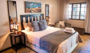 Four Seasons Guesthouses في Lephalale: غرفة نوم بسرير كبير وكرسي