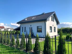 une maison blanche avec une clôture noire dans l'établissement AHOY - Haus am Meer, à Chłopy