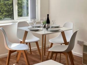 The Lambourne في Birstall: طاولة غرفة طعام بيضاء مع كراسي بيضاء وزجاجة من النبيذ
