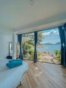 a bedroom with a large window with a view of the ocean at patong sunset villa Phuket in Patong Beach