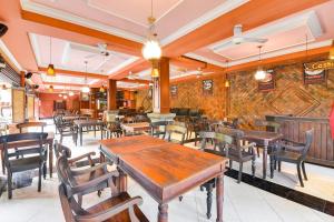 a restaurant with wooden tables and chairs in a room at Super OYO Townhouse Oak Maxi Hotel Legian in Kuta