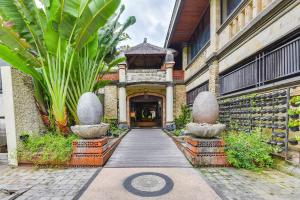 a walkway leading to a building with two large plants at Super OYO Townhouse Oak Maxi Hotel Legian in Kuta