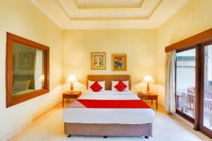 a bedroom with a large bed with red pillows at Townhouse Oak Maxi Hotel Legian Bali in Kuta